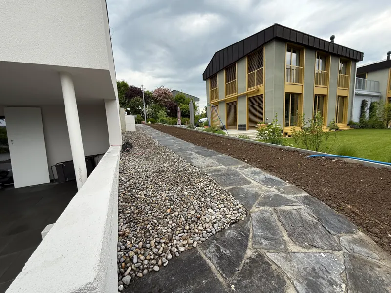 Polygonalplatten und Kiesstreifen entlang der Fassade