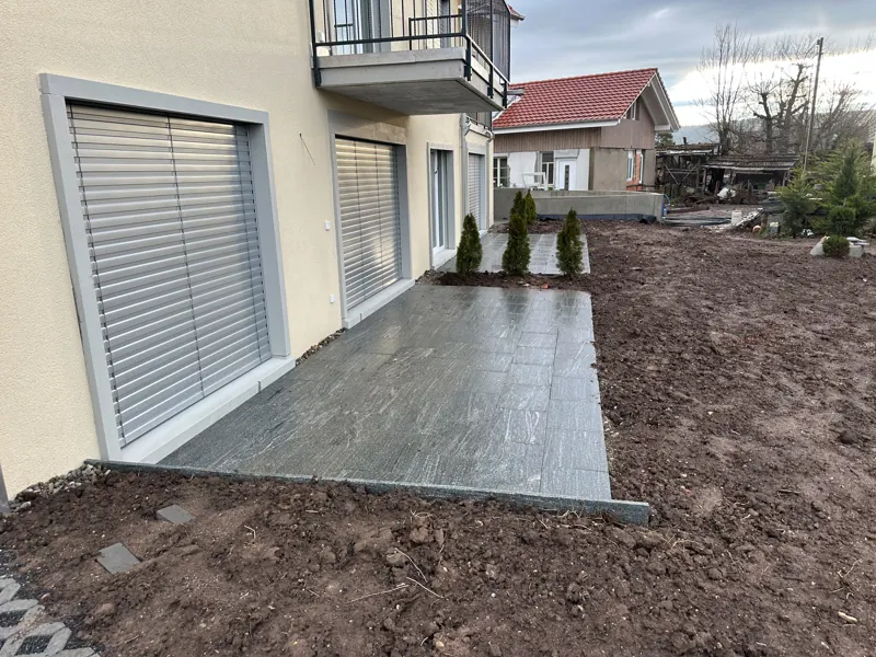 Sitzplatz mit dunklen Platten unter dem Vordach