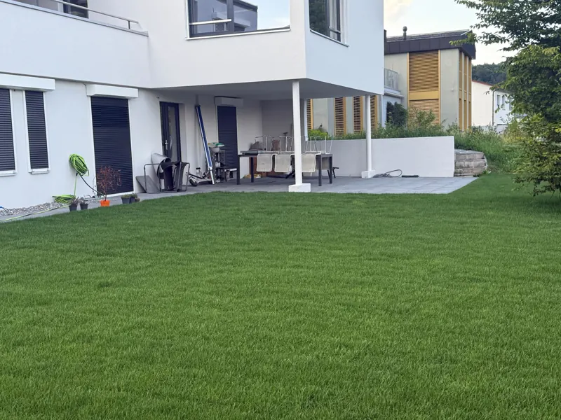 Fertiger Rasen und Sitzplatz an einem weissen Einfamilienhaus
