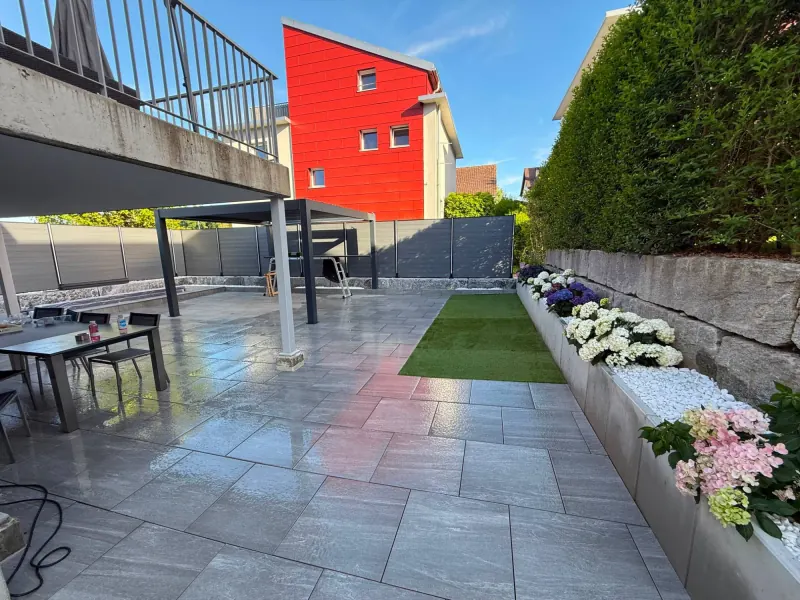 Sitzplatz mit grossformatigen Platten, Pergola und Hortensien im Hochbeet